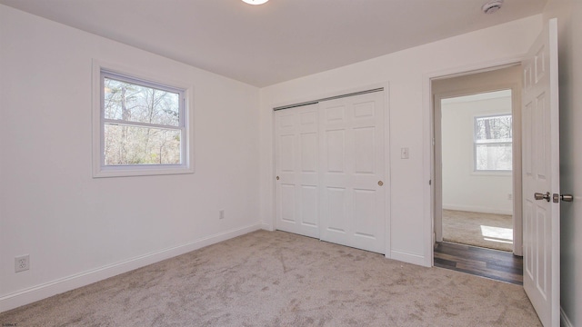 unfurnished bedroom featuring baseboards, a closet, and light colored carpet