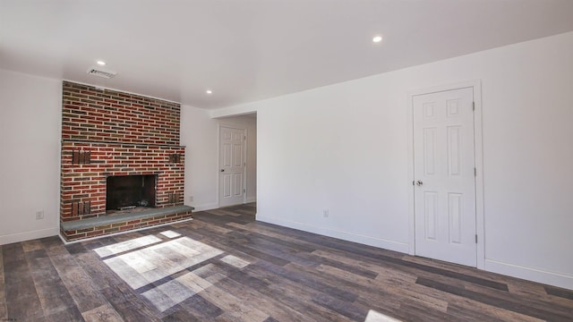 unfurnished living room with recessed lighting, visible vents, baseboards, a brick fireplace, and dark wood finished floors