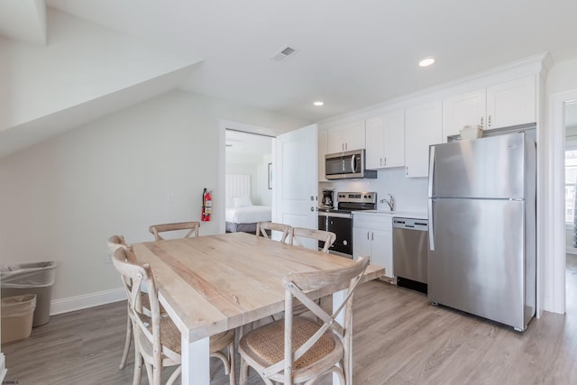 dining room featuring baseboards, light wood-style flooring, visible vents, and recessed lighting