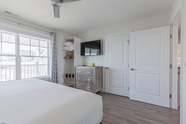 bedroom featuring ceiling fan, visible vents, and wood finished floors