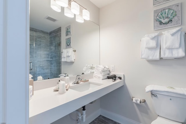 full bathroom featuring toilet, a sink, visible vents, baseboards, and a shower stall