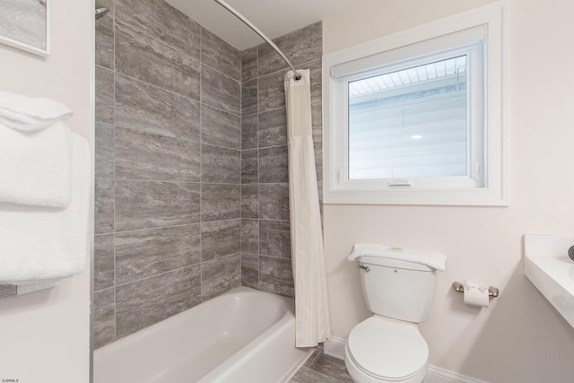 bathroom featuring baseboards, toilet, and shower / bath combo with shower curtain