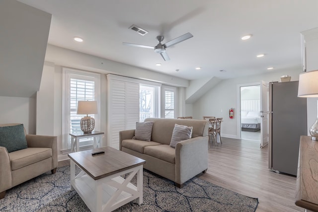 living room with recessed lighting, visible vents, light wood-style flooring, and baseboards