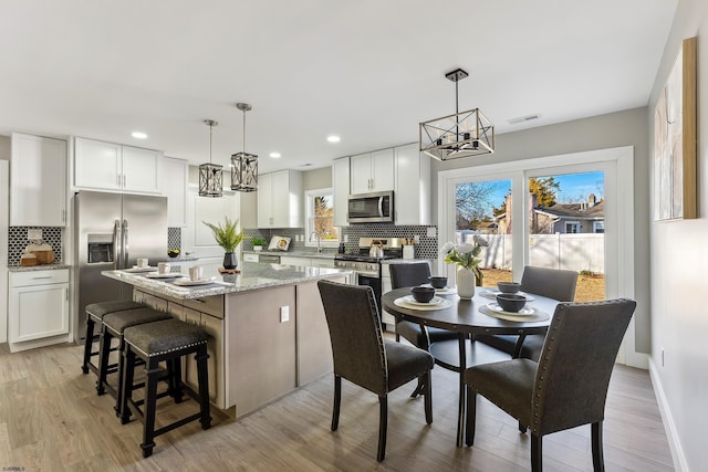 kitchen featuring white cabinetry, a center island, appliances with stainless steel finishes, and decorative light fixtures