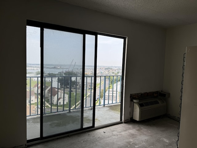 interior space featuring concrete flooring, a textured ceiling, and a wall mounted air conditioner