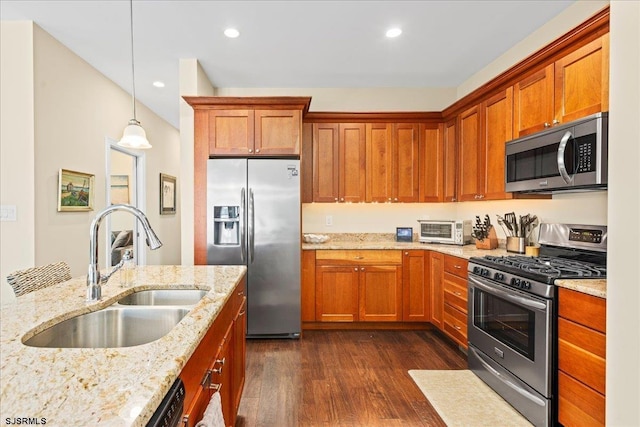 kitchen featuring stainless steel appliances, dark wood-type flooring, a sink, light stone countertops, and decorative light fixtures