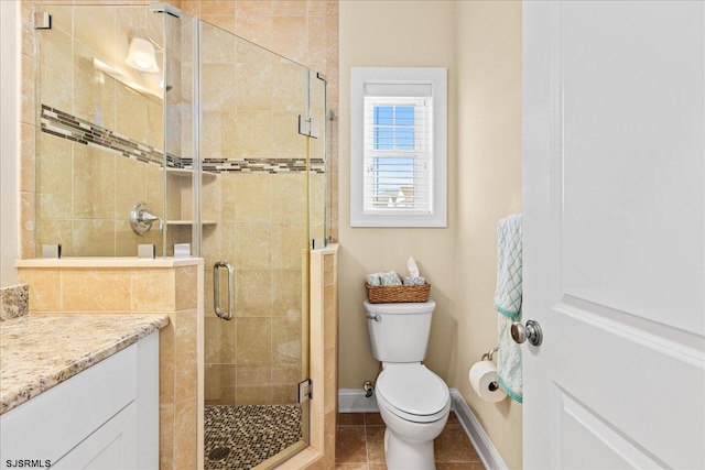 bathroom with tile patterned flooring, toilet, vanity, baseboards, and a stall shower