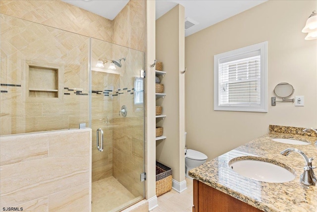 bathroom with toilet, a stall shower, double vanity, and a sink