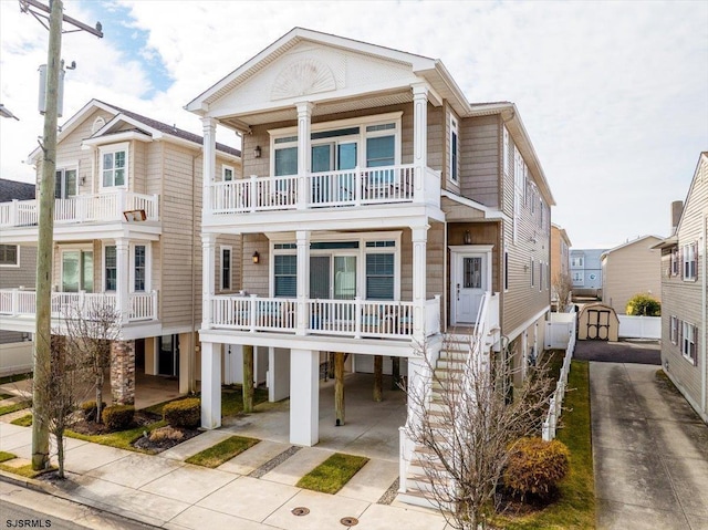 view of front of house featuring driveway, a balcony, an outbuilding, a storage unit, and a porch