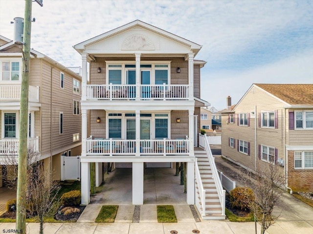 coastal inspired home featuring covered porch, a carport, a balcony, and driveway