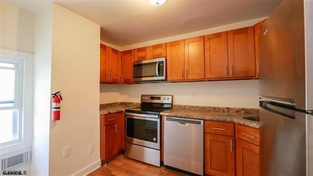 kitchen featuring brown cabinets, stone counters, visible vents, and stainless steel appliances