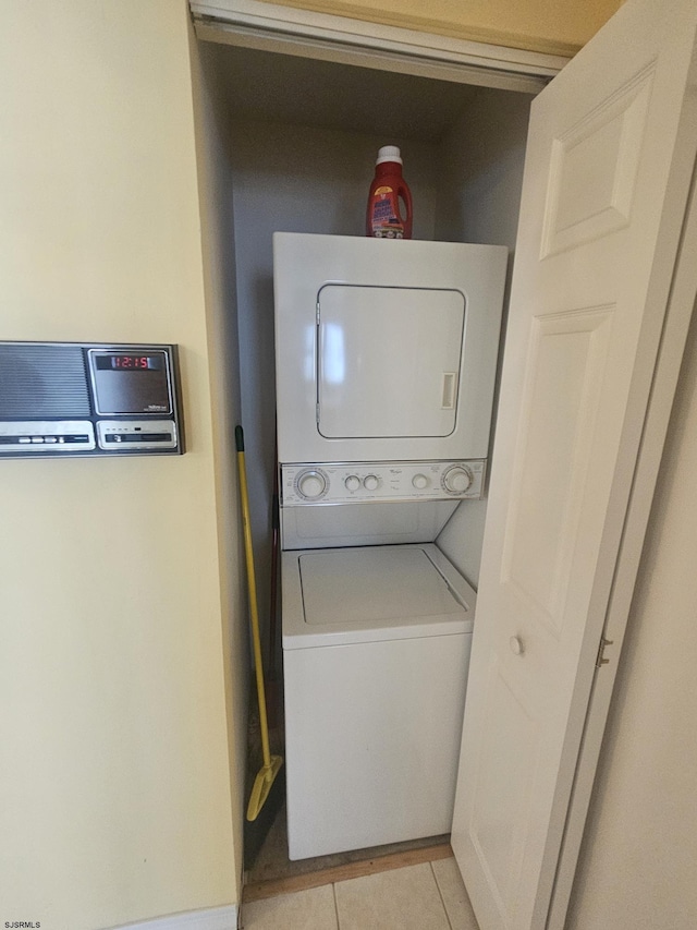 washroom featuring stacked washer / dryer, laundry area, and light tile patterned floors