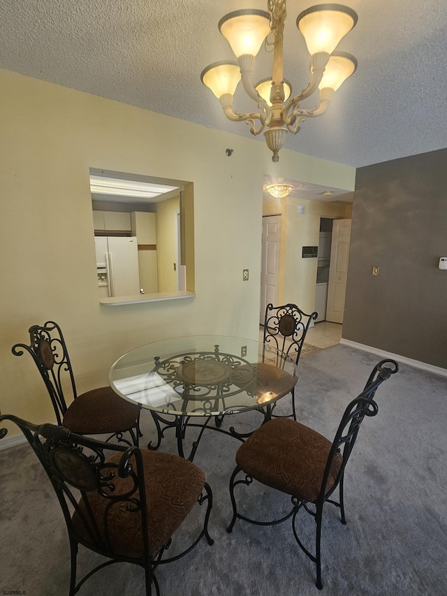 dining space featuring a chandelier, light colored carpet, a textured ceiling, and baseboards