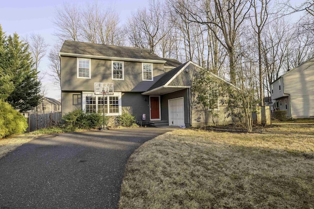 colonial-style house with aphalt driveway, fence, and an attached garage