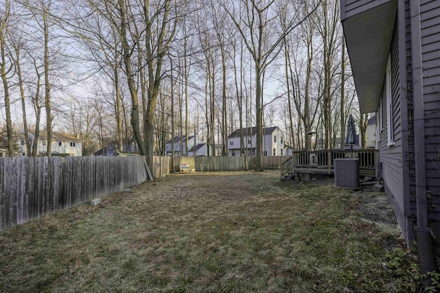 view of yard with a fenced backyard, a residential view, a deck, and cooling unit