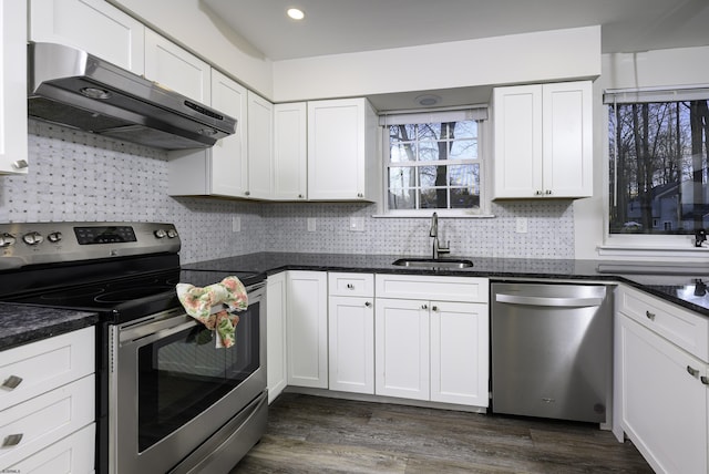 kitchen with dark wood-style flooring, stainless steel appliances, white cabinetry, a sink, and under cabinet range hood