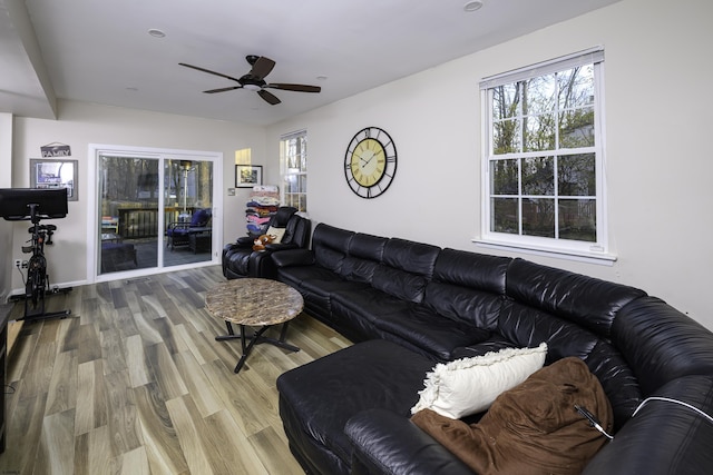 living room with ceiling fan, baseboards, and wood finished floors