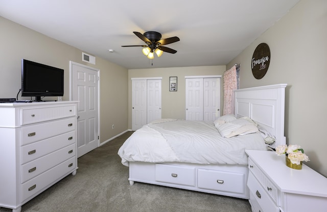 bedroom featuring ceiling fan, carpet floors, visible vents, baseboards, and multiple closets