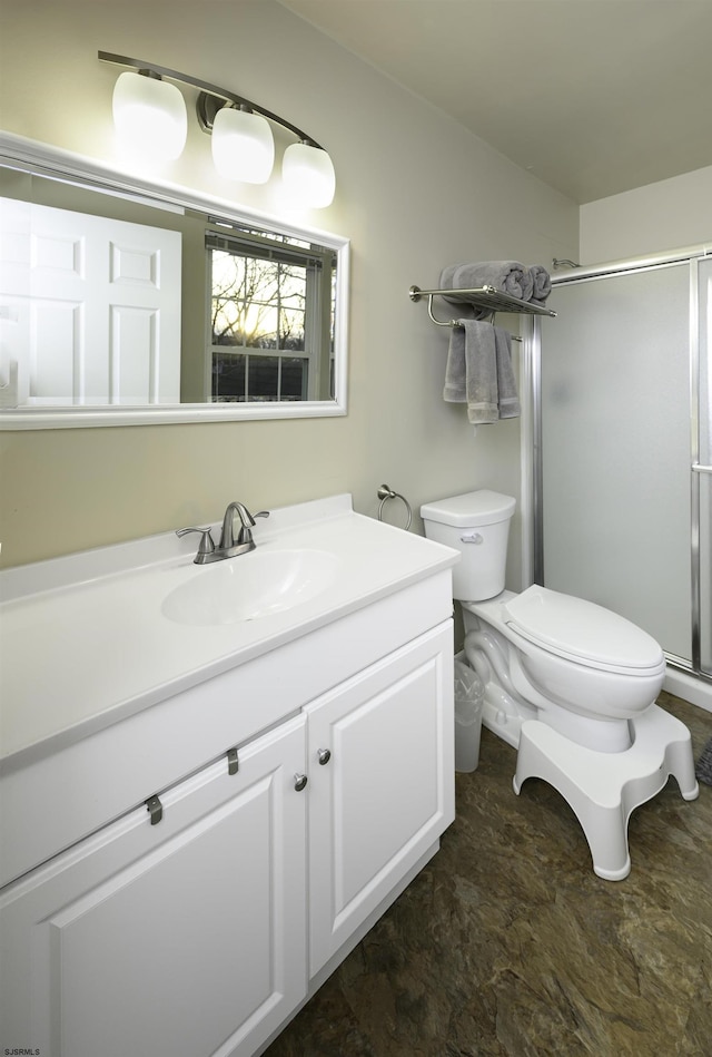 bathroom featuring vanity, a shower stall, and toilet