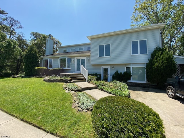 tri-level home featuring french doors, a chimney, and a front yard