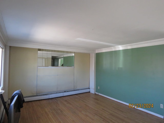 spare room with ornamental molding, baseboards, baseboard heating, and wood finished floors