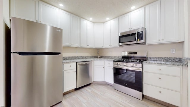 kitchen with stainless steel appliances, recessed lighting, white cabinetry, and light wood finished floors