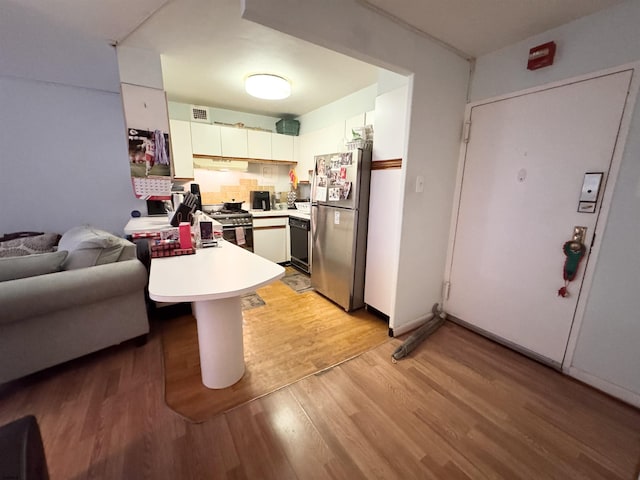 kitchen with a peninsula, light wood-style floors, freestanding refrigerator, dishwasher, and gas stove