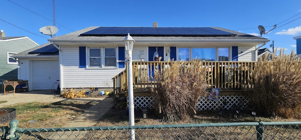 bungalow-style house featuring a garage, solar panels, and fence