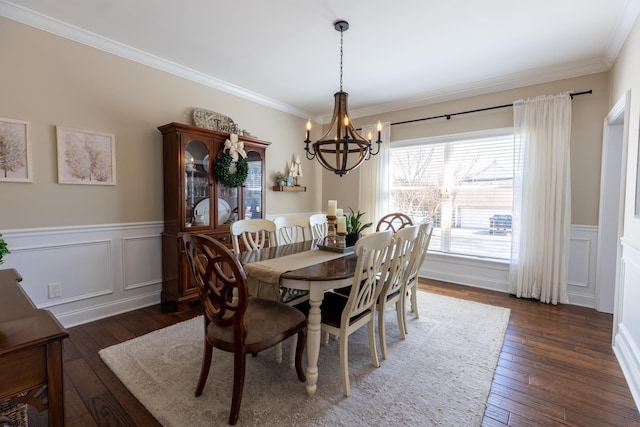 dining space featuring dark wood-style floors, ornamental molding, a wainscoted wall, and an inviting chandelier