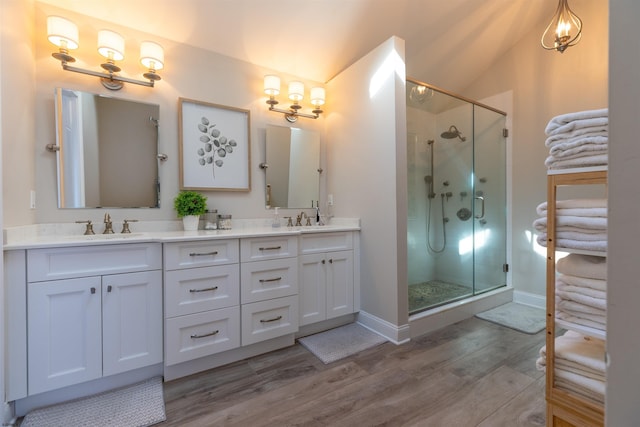 bathroom with lofted ceiling, a shower stall, a sink, and wood finished floors