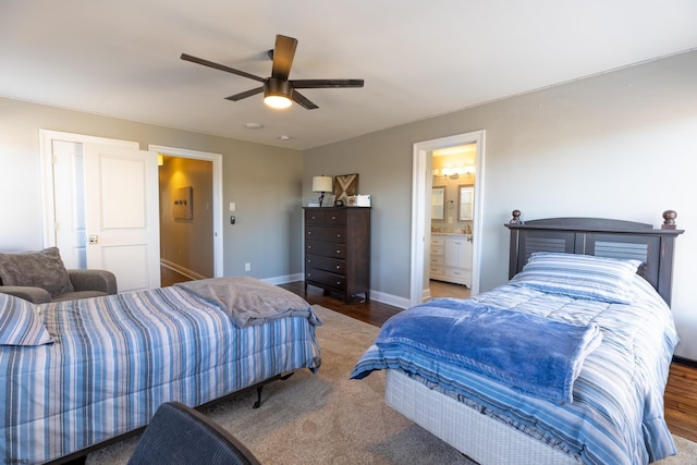 bedroom featuring ceiling fan, ensuite bath, baseboards, and wood finished floors