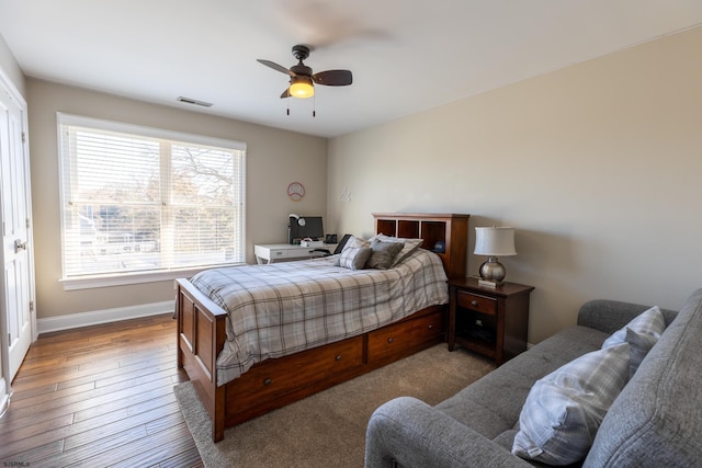 bedroom featuring ceiling fan, wood finished floors, visible vents, and baseboards