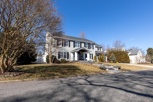 colonial house featuring fence and a front lawn