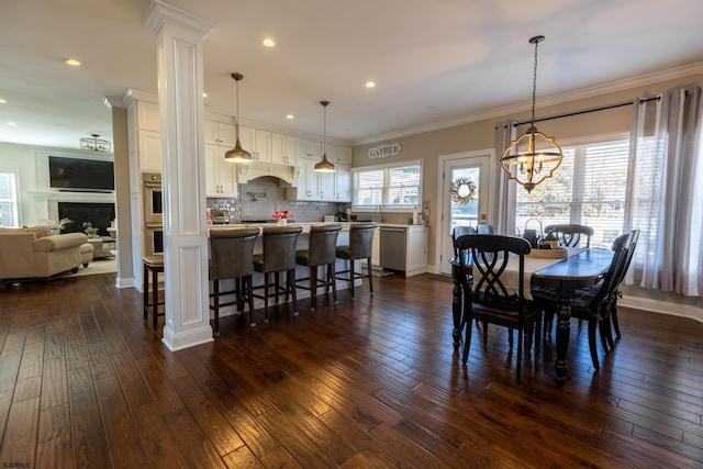 dining room featuring plenty of natural light, decorative columns, dark wood finished floors, and crown molding