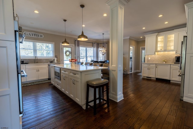 kitchen featuring stainless steel appliances, dark wood-type flooring, decorative columns, and white cabinets