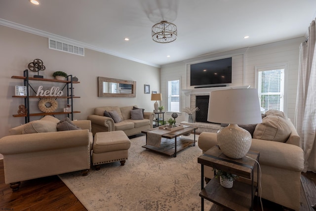 living room featuring a wealth of natural light, visible vents, wood finished floors, and ornamental molding