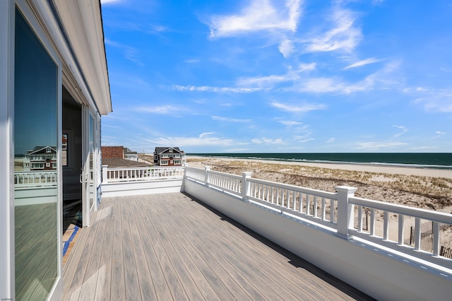 wooden deck featuring a water view and a view of the beach