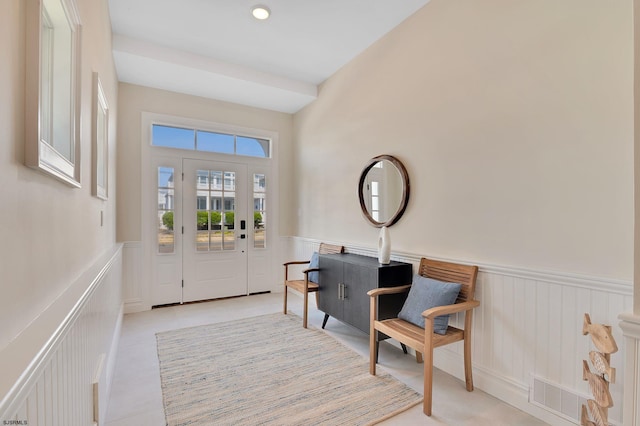 foyer entrance featuring light tile patterned flooring, visible vents, and wainscoting