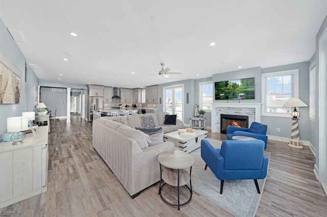 living room featuring a healthy amount of sunlight, light wood-style floors, baseboards, and recessed lighting