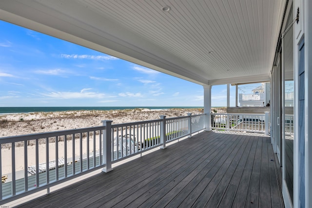 wooden deck featuring a water view and a view of the beach