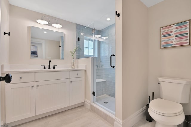 bathroom with a stall shower, vanity, toilet, and baseboards