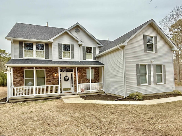 traditional-style house featuring a shingled roof and a porch