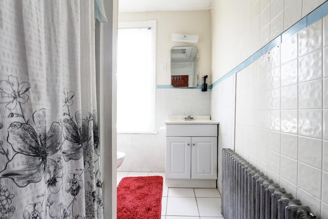 full bathroom featuring toilet, vanity, tile walls, tile patterned floors, and radiator