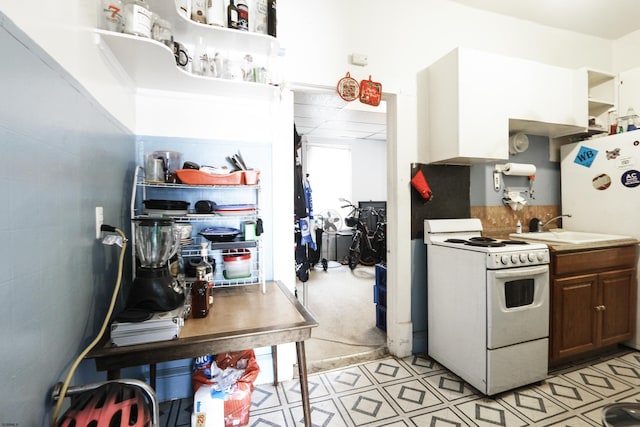 kitchen featuring white electric stove, light floors, open shelves, light countertops, and a sink