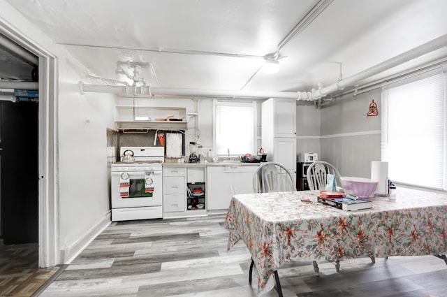 kitchen featuring light wood-type flooring, white gas range oven, white cabinetry, and light countertops