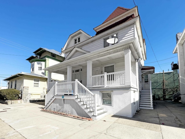 view of front facade with covered porch, stairs, and stucco siding