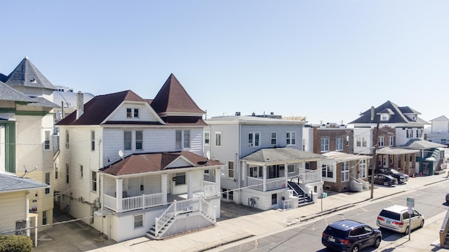 view of front facade featuring a residential view, stairway, and roof with shingles