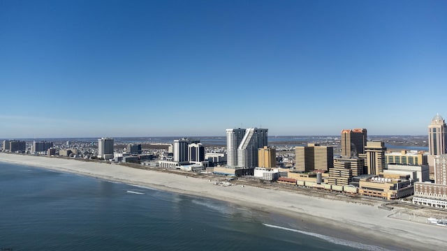 drone / aerial view with a water view, a view of the beach, and a city view