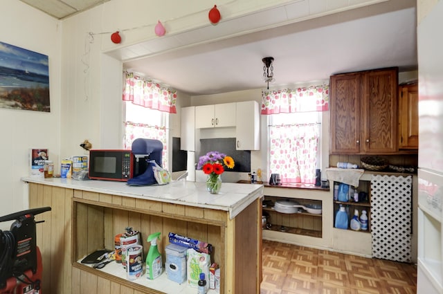 kitchen featuring a peninsula, black microwave, and decorative light fixtures