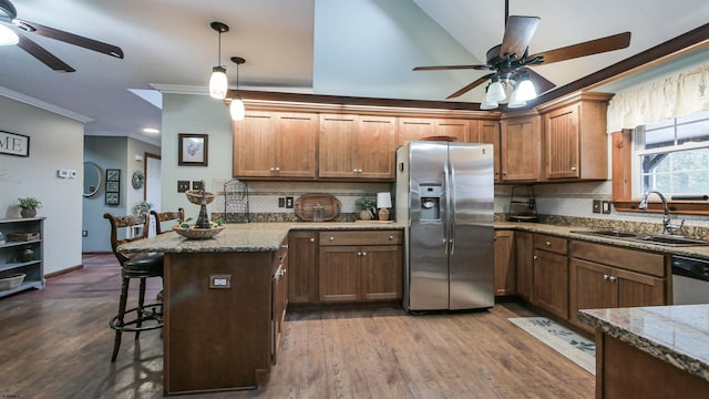 kitchen featuring stainless steel appliances, dark wood-type flooring, ornamental molding, a sink, and a kitchen breakfast bar